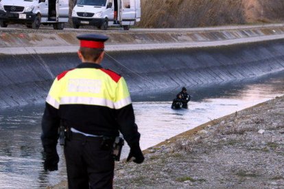 Un mosso andando por el arcén del canal de Seròs y la unidad subacuática dentro del canal, donde se ha encontrado el coche de la vecina de les Borges Blanques.