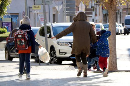 Imatge d'una dona i de dos menors caminant a Valls enmig d'un fort vent.