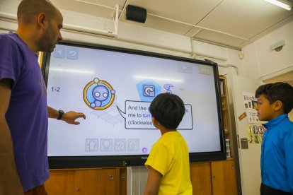 Moncusí explica a dos alumnes el funcionament d'un panel interactiu que ha incorporat l'escola.