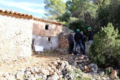 Una de les façanes del Mas de Burot als Ports d'Horta de Sant Joan, amb un grup d'arquitectes, tècnics i l'alcalde Joaquim Ferràs conversant a la porta.