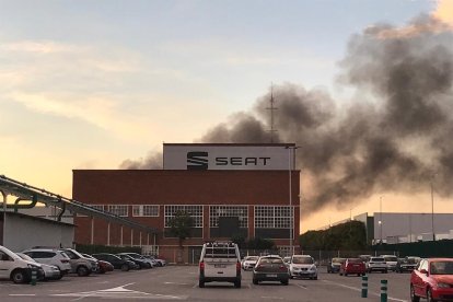 Imagen de la fachada frontal de la fábrica Seat con humo en segundo término proveniente de un incendio en el Museo Histórico.