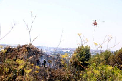 Bombers treballen en l'extinció de l'incendi al turó de Montjuïc de Barcelona on hi ha les ruïnes del Castell de Port.