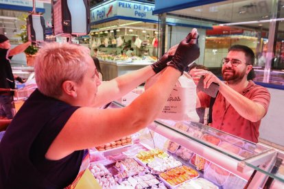 Un client demana que li posin la seva compra en una bossa de roba, a la Polleria Rosa Riba.