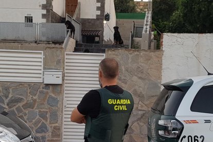 Imatge d'un agent de la Guàrdia Civil davant el xalet que albergava la plantació amb dos gossos rottweilers vigilant-lo.