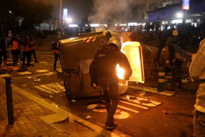 Un manifestant davant d'un contenidor cremant a la Travessera de les Corts, davant l'accés 18 al Camp Nou.