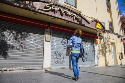 Una dona observa la pastisseria Sanromá amb la persiana abaixada, ahir a la tarda.