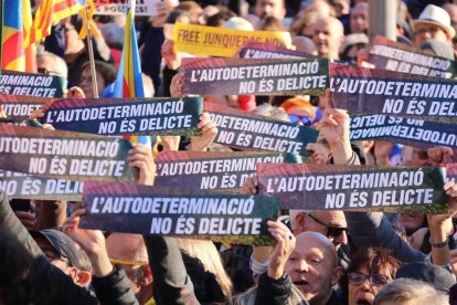 Un grupo de manifestantes sostienen carteles que dicen 'La autodeterminación no es delito' a la manifestación contra el juicio del 1-O en Barcelona.