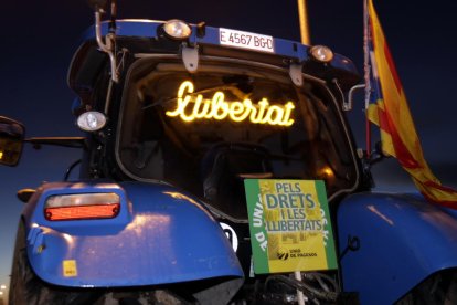 Pla curt d'un tractor que porta un panell lluminós amb la paraula 'llibertat'.