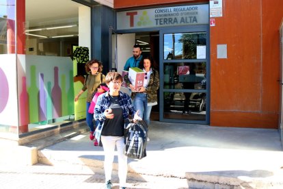 Un grup de persones surt amb caixes de vi de la seu del Consell Regulador de la DO Terra Alta.