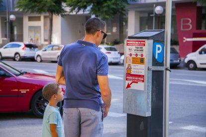 Un home i un nen, ahir, davant d'un dels parquímetres afectats al carrer Vidal i Barraquer.