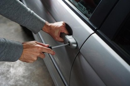 Un hombre intentando forzar la cerradura de la puerta de un vehículo