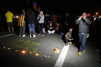 Alguns manifestants cantant al so de la gralla davant els escrits i les espelmes que han deixat a l'N-340 a Amposta.