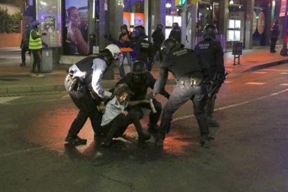 Plano general de los Mossos d'Esquadra deteniendo a un manifestante durante la cuarta noche de disturbios en Tarragona.