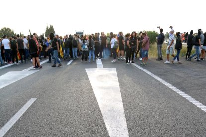 Primer pla de les senyals a l'asfalt de l'AP-7 a l'Ampolla amb els manifestants al fons. Imatge del 18 d'octubre del 2019 (vertical)