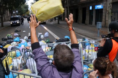 Un home llança una bossa d'escombraries a l'entorn de la delegació del govern espanyol a Barcelona.