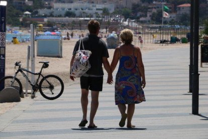 Dos turistas de espalda paseando por el paseo marítimo de Torredembarra.