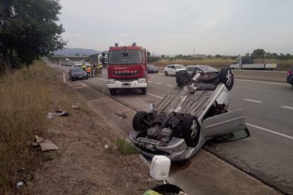 Imagen del coche volcado con un vehículo de los Bomberos al fondo.