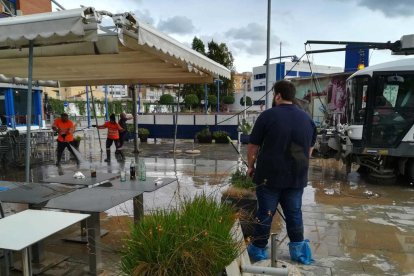 Albert Mateu, propietario de L'Arrosseria –de espalda– durante las tareas de limpieza de la terraza del establecimiento del Serrallo.