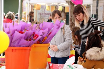 Unes noies davant d'uns cubells amb roses, a les parades  de Sant Jordi de la plaça de Dalt de Móra d'Ebre.