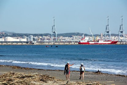 Dos motos acuáticas y una lancha haciendo busca de desaparecidos al mar, entre el puerto de Tarragona y la playa del Pinar, llena de cañas y con dos personas señalando al horizonte.