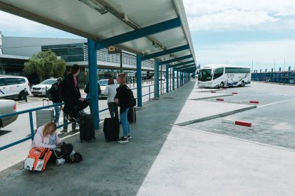 Passatgers esperen l'arribada d'autobusos interurbans a les andanes de l'aeròdrom.