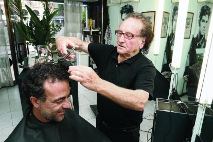 El perruquer Jordi Gimeno, que té el local a la plaça Prim, atenent un client, ahir.