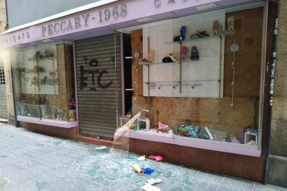 Imagen del cristal del escaparate del establecimiento roto con algunos zapatos en el suelo.