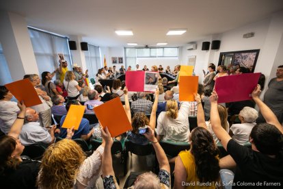 Plano general del pleno este sábado 15 de junio con las protestas de los vecinos y las dos fotografías de Puigdemont i Torra en el fondo