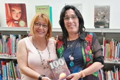 Pinyeres y Montse Assens con el libro que recoge los juegos de su infancia.