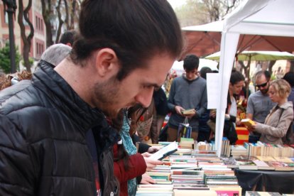 Un home remena una parada de llibres a la Rambla Nova de Tarragona, durant la diada de Sant Jordi. Foto del 23 d'abril del 2019 (Vertical).