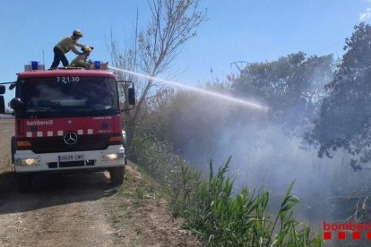 Un bomber amb la mànega treballant a l'incendi.