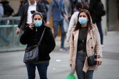 Dos mujeres con mascarillas caminando por Barcelona