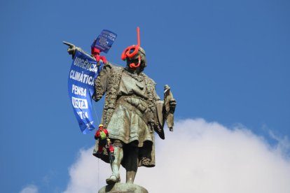 L'estàtua de Colom amb dos activistes despenjant una pancarta.