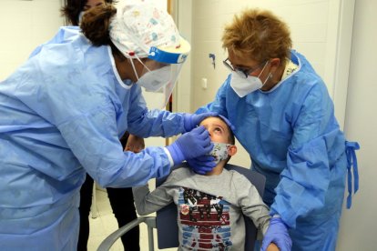 Imatge d'arxiu de dues infermeres fent un test ràpid d'antígens a un nen.