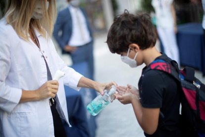 Un nen es desinfecta les mans després que li prenguin la temperatura a l'entrada del col·legi privat internacional American School of Barcelona.