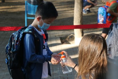 L'alumne d'una escola de Barcelona rebent gel desinfectant a l'entrada del centre.