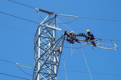 Dos operarios reparan una línea de alta tensión de Endesa /