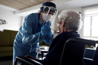 Una cuidadora dona de menjar a una anciana en una residència a Madrid.