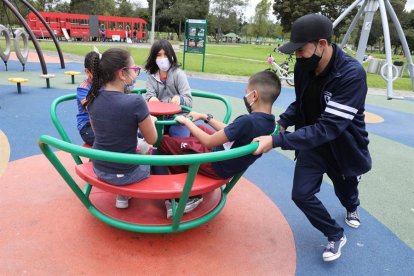 Un grupo de niños, protegidos por mascarillas, juega en un parque.