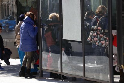 Gent protegint-se del vent, en una parada d'autobús a Valls.