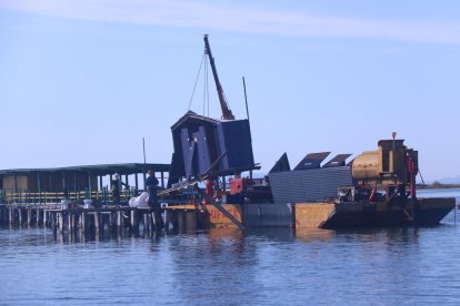 Una grua aixecant la caseta dels lavabos del Xiringuito de la Costa, a la Punta de la Banya.