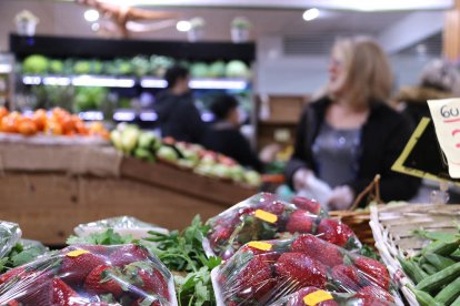 Diversos clients en una fruiteria de mercat.