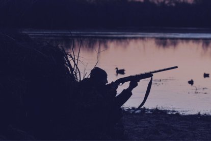 Plano general de un cazador preparado para disparar en una laguna, de noche.