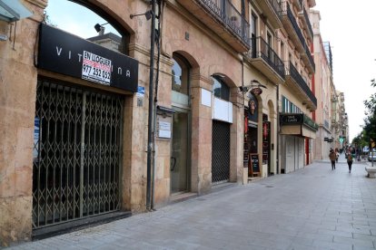 Una zona de la Rambla Nova de Tarragona on s'hi aprecien tres locals comercials buits, amb poc moviment de vianants.