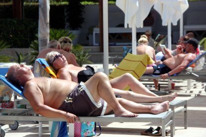 Una pareja de turistas extranjeros tomando el sol en unas vagas en un resorte de Cambrils.