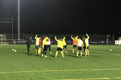 Los jugadores grana calentando sobre el Municipal de Llagostera