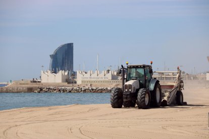 Un tractor en la represa del servei de neteja de les platges a Barcelona.