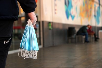 Una mà en primer pla sostenint un grapat de mascaretes a l'estació d'autobusos de Tarragona.