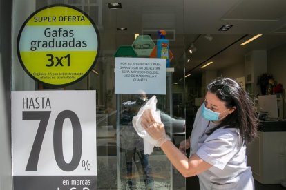 Una mujer limpiando el escaparate de una óptica.