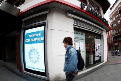 Un home passejant davant un cartell referent al coronavirus